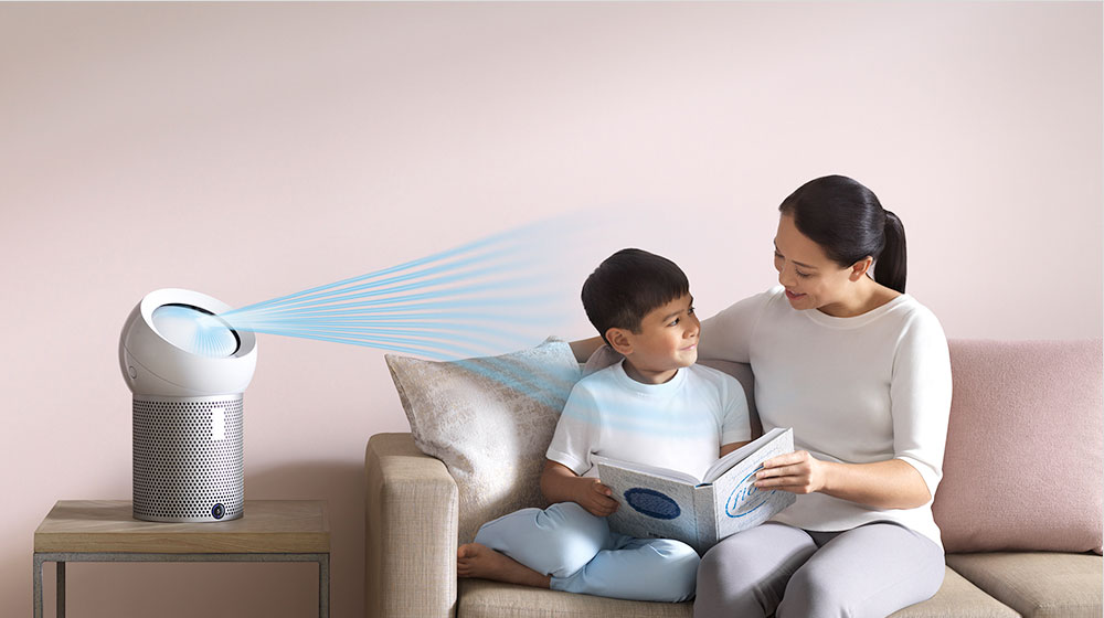 A woman reads to her son, next to a Dyson personal purifier fan